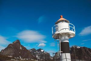 faro en el muelle en el fondo de las montañas y el cielo azul en las islas lofoten. lugar para texto o publicidad foto