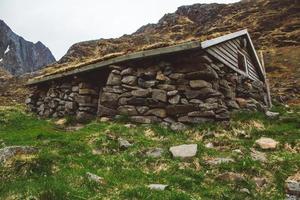 Antigua casa de piedra y madera cubierta de musgo en el fondo de las montañas. lugar para texto o publicidad foto