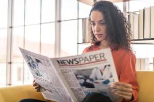 Latin America woman reading newspaper on sofa photo