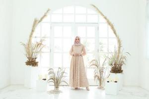 Retrato de cuerpo entero de dama con vestido de novia, maquillaje de boda en hijab. vestido de novia malayo o indonesia, concepto de belleza o eidul fitri. Hermosa mujer musulmana del sudeste asiático posando en traje de islam foto