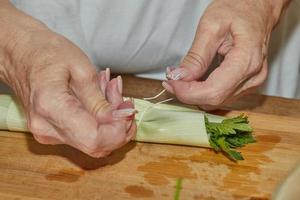 El chef ata el ramo de verduras con una cuerda para llenar el plato. foto