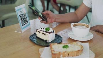 una mujer escanea un código de barras para pedir más comida. una mujer escanea un código qr para pagar el pastel y el café. una mujer escanea el código para acumular puntos para canjear. concepto de soporte tecnológico. video