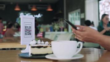 cliente che utilizza i telefoni per la scansione del codice qr per pagare il dessert. sistema di scansione mobile online per pagare soldi al caffè. tecnologia concettuale per la distanza sociale. video