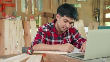 Small business owner carpentry concept. Asian man owns recheck wood furniture. carpenter is Recheck straight of wood before manufacturing. Comparison of material with designs. video