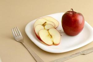 Delicious apple and slice in white plate with knife and fork photo