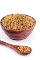 Fenugreek seeds in wooden bowl with spoon isolated on white background photo