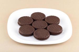 Brown chocolate sandwich biscuits with cream filling in plate photo