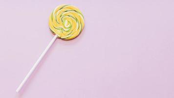 yellow green striped lollipop against pink background photo