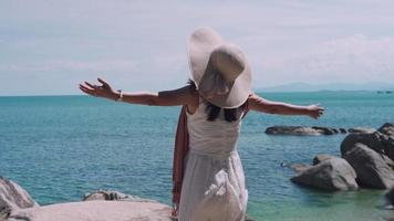 vrouw voelt recreatie op vakantie. vrouwen reizen alleen door de natuur. een vrouw die bij de zee staat in de wind en de zon. reisconcept video