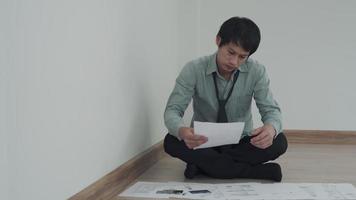 concepts de dette et problèmes financiers. hommes asiatiques assis par terre et stressés par les problèmes d'endettement. les hommes s'inquiètent des factures qui doivent être payées mensuellement. concepts de dette, problèmes financiers. video