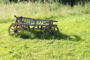 Old wooden wagon stands on the grass. photo