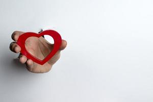 mano femenina sosteniendo un corazón sobre un fondo blanco. foto