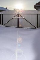 Sunset in the winter. Sunbeams in the snow. Garage metal gates covered with snow. photo