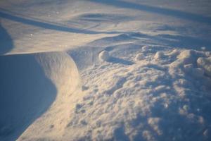 Snowy landscapes and snow close-up in sunbeams. Grass and objects in the snow. photo