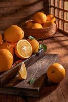 bajo la luz tenue, las naranjas en el plato están sobre la mesa de madera, como pinturas al óleo