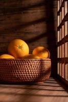 Under the dim light, the oranges on the plate are on the wooden table, like oil paintings