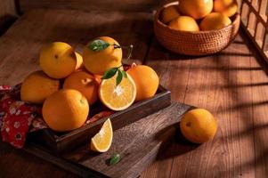 bajo la luz tenue, las naranjas en el plato están sobre la mesa de madera, como pinturas al óleo