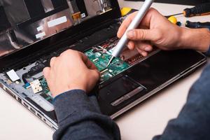 Wizard repairs laptop with tools and hands photo