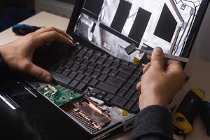 Wizard repairs laptop with tools and hands photo