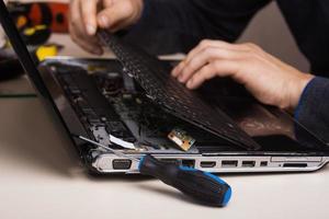 Wizard repairs laptop with tools and hands photo