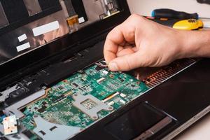 Wizard repairs laptop with tools and hands photo