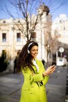 Young woman listening music with smartphone on the street photo