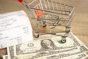 Grocery shopping list receipts with shopping cart and US dollar banknotes money. photo