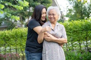 Asian elderly woman with caregiver daugther walking and hug with happy in nature park. photo