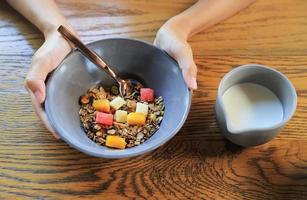 mano que sostiene cereal de grano entero con fruta y leche para el cuidado de la salud comiendo en la vida diaria foto