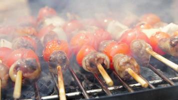 Chicken hearts with tomato and onion cooking on hot grill