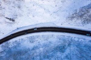 Curvy windy road in snow covered forest, top down aerial view. photo