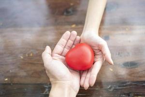 un par de manos sosteniendo el corazón rojo, el amor y el concepto de atención médica foto