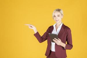 Business woman is pointing something on yellow  background photo