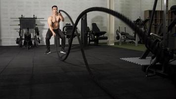 Asian athletic man with  rope doing exercise in fitness gym