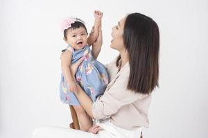 la madre asiática y la adorable niña son felices con antecedentes blancos foto