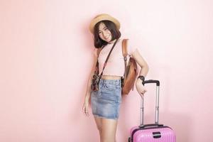 Happy Asian woman tourist  on pink background photo