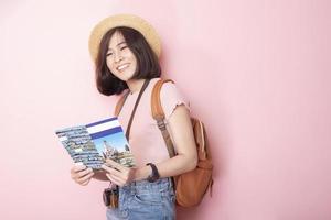 Happy Asian woman tourist  on pink background photo