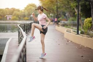 hermosa mujer está escuchando música y haciendo ejercicio en el parque foto