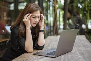 mujer asiática estresada que siente dolor de cabeza en la cafetería foto