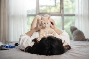 hermosa mujer asiática amante de los gatos está jugando con un gato en su habitación foto