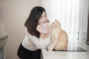 hermosa mujer asiática amante de los gatos está jugando con un gato en su habitación foto