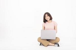 Una linda adolescente asiática está trabajando con una computadora de fondo blanco foto