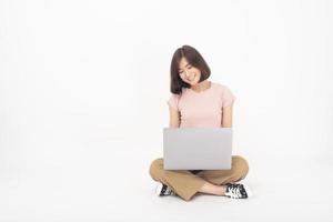 Cute Asian teen woman is working with computer on white background photo