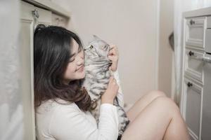 Beautiful asian  cat lover woman is playing with cat in her room photo