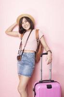 Happy Asian woman tourist  on pink background photo