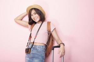 Happy Asian woman tourist  on pink background photo
