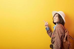 Happy Young Asian tourist woman on yellow background photo