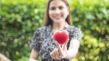 la mano de la mujer sostiene el corazón rojo, el amor y el concepto de atención médica foto