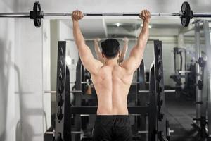hombre culturista con gran espalda muscular en el gimnasio foto