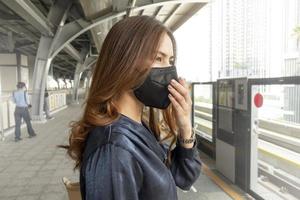 hermosa mujer con máscara antipolvo protege la contaminación del aire y pm 2.5 en la ciudad de la calle foto